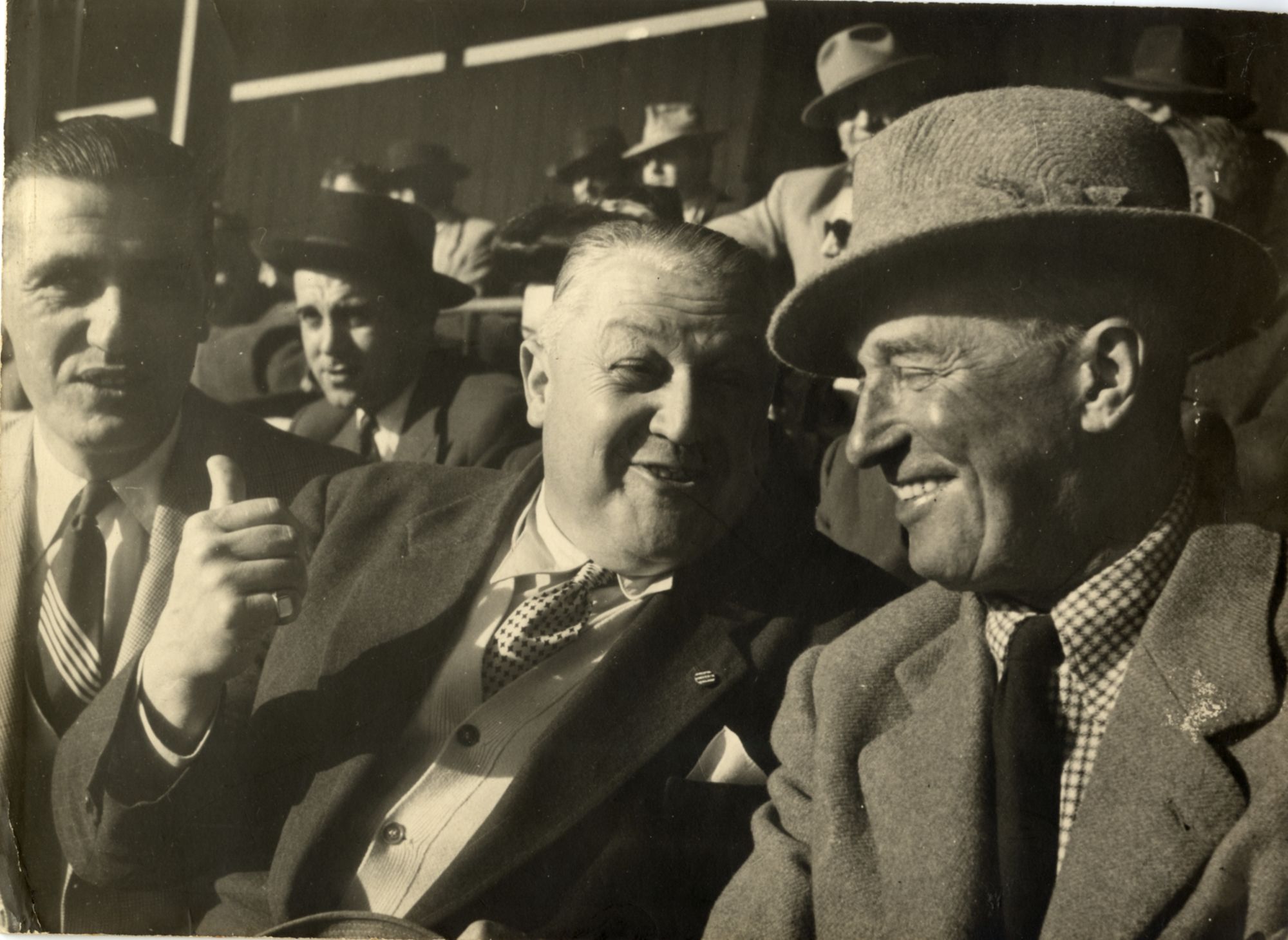 Dans les tribunes de l'hippodrome de Mandelieu, le chanteur Maurice Chevalier (à dr.), son ami Michel Mollard, commissaire général du comité des fêtes et M. Charles Pellissier, 1950. AMC, 25Fi1599